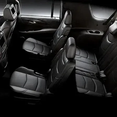 Black leather car interior with three rows of seats and a dark, spacious cabin
