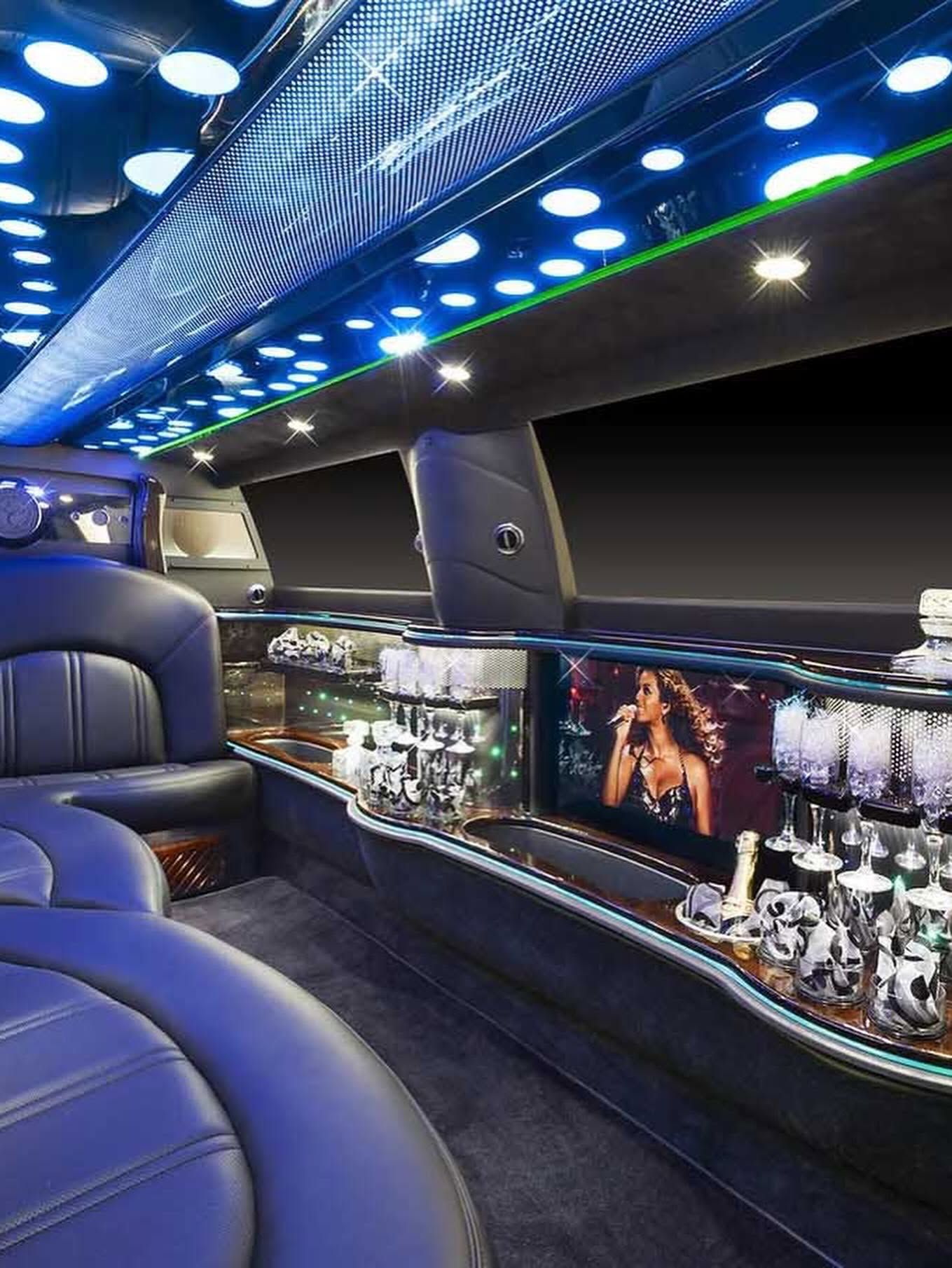 Blue-leather limousine interior with LED ceiling lights and a stocked bar display