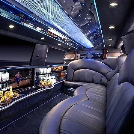 Luxurious limo interior with black leather seats, mirrored ceiling lights, and a small display shelf.