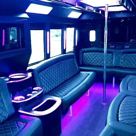 Luxurious party bus interior with purple lighting, leather seats, and bar tables