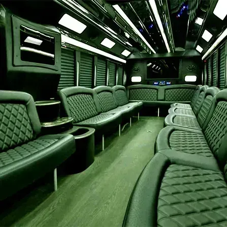 Green-lit luxury bus interior with quilted seats and a central aisle