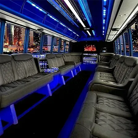 Blue-lit luxury bus interior with black leather seats and city lights outside the windows