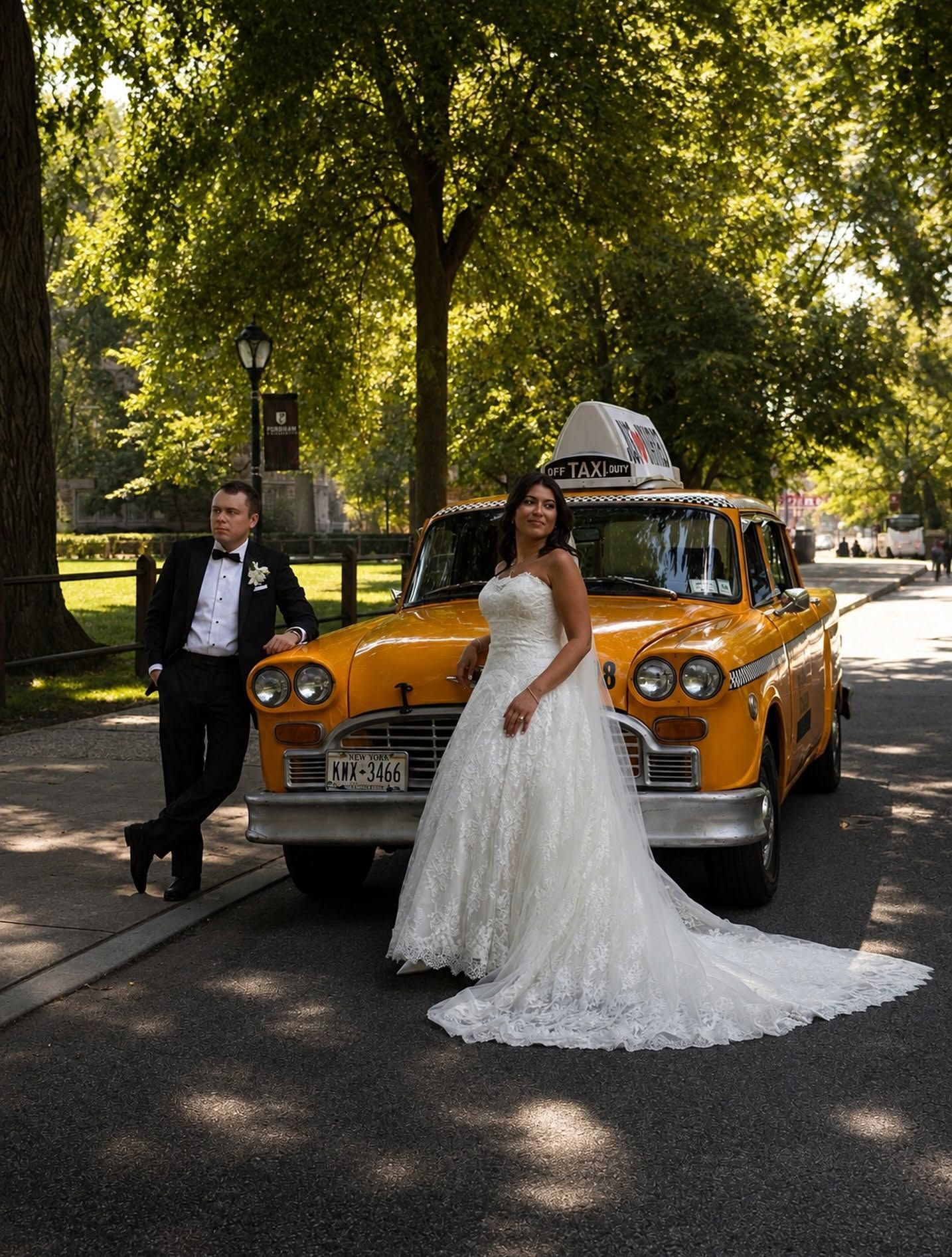 Bride and groom beside a vintage yellow taxi on a tree-lined street