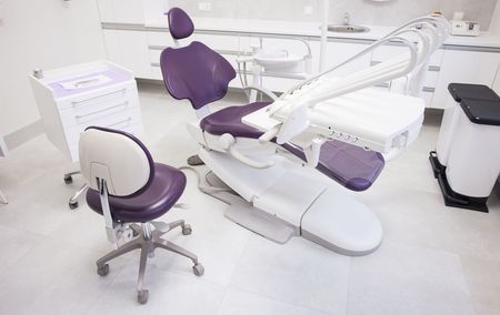 A dental office with a purple chair and a white chair.