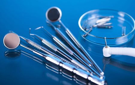 A bunch of dental instruments on a blue surface