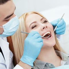 A woman is getting her teeth examined by a dentist