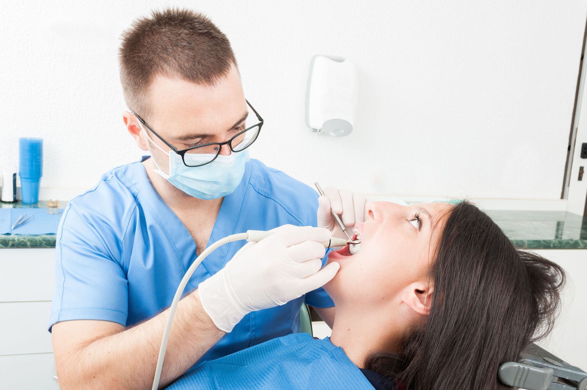 A dentist is examining a woman 's teeth in a dental office.