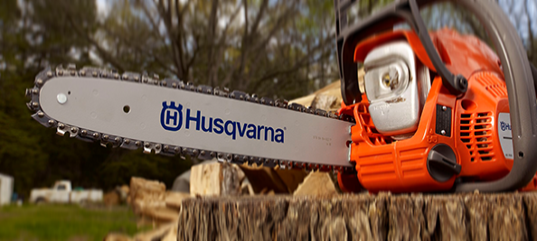 Husqvarna chainsaw resting on a tree stump.