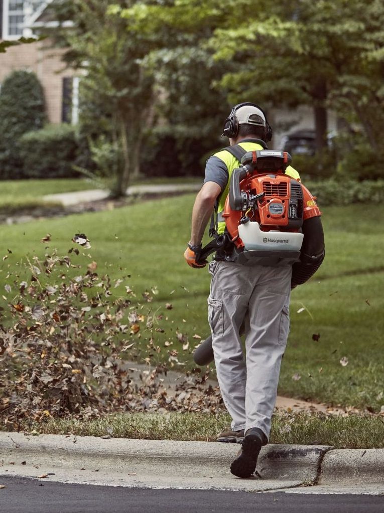 Man using a leaf blower to blow leaves.