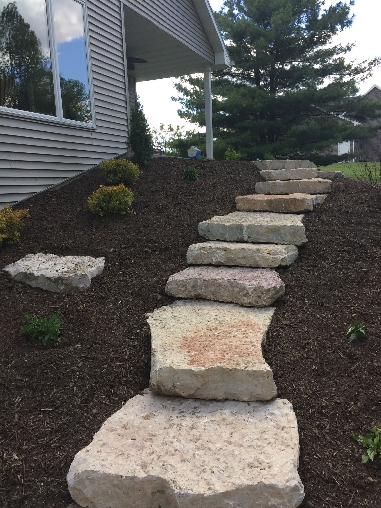 Stone steps leading up a landscaped slope beside a house