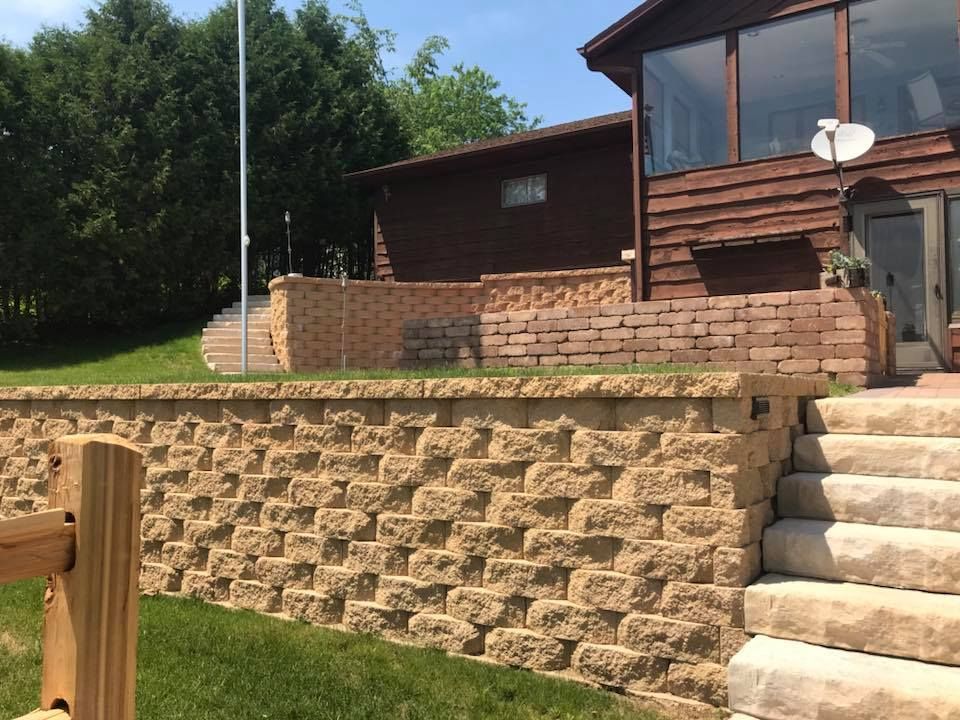 House with terraced stone retaining walls and steps in a grassy yard