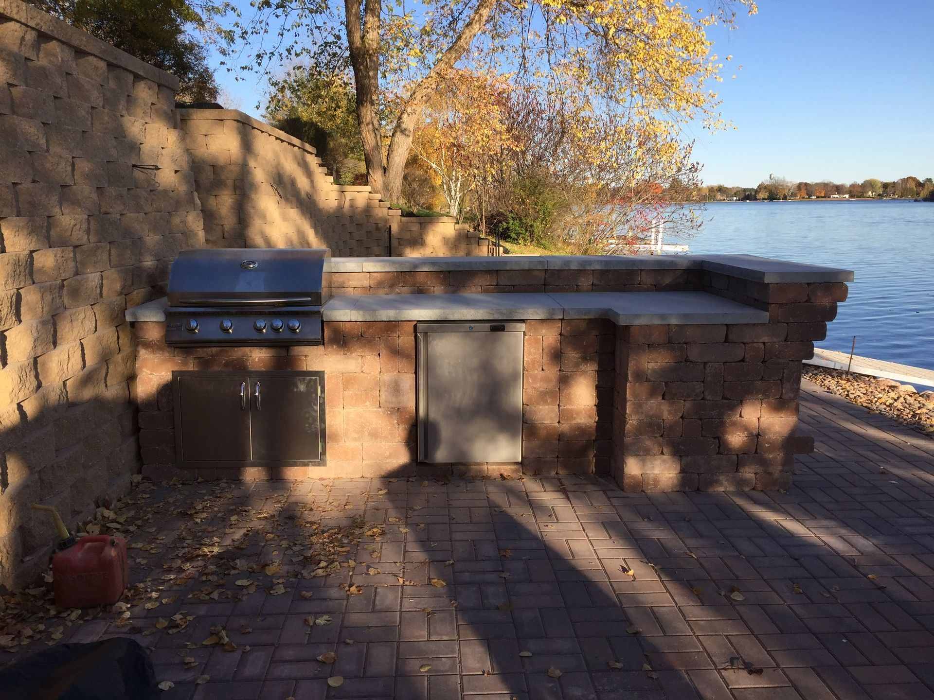 Brick outdoor grill and picnic table beside a river on a sunny day