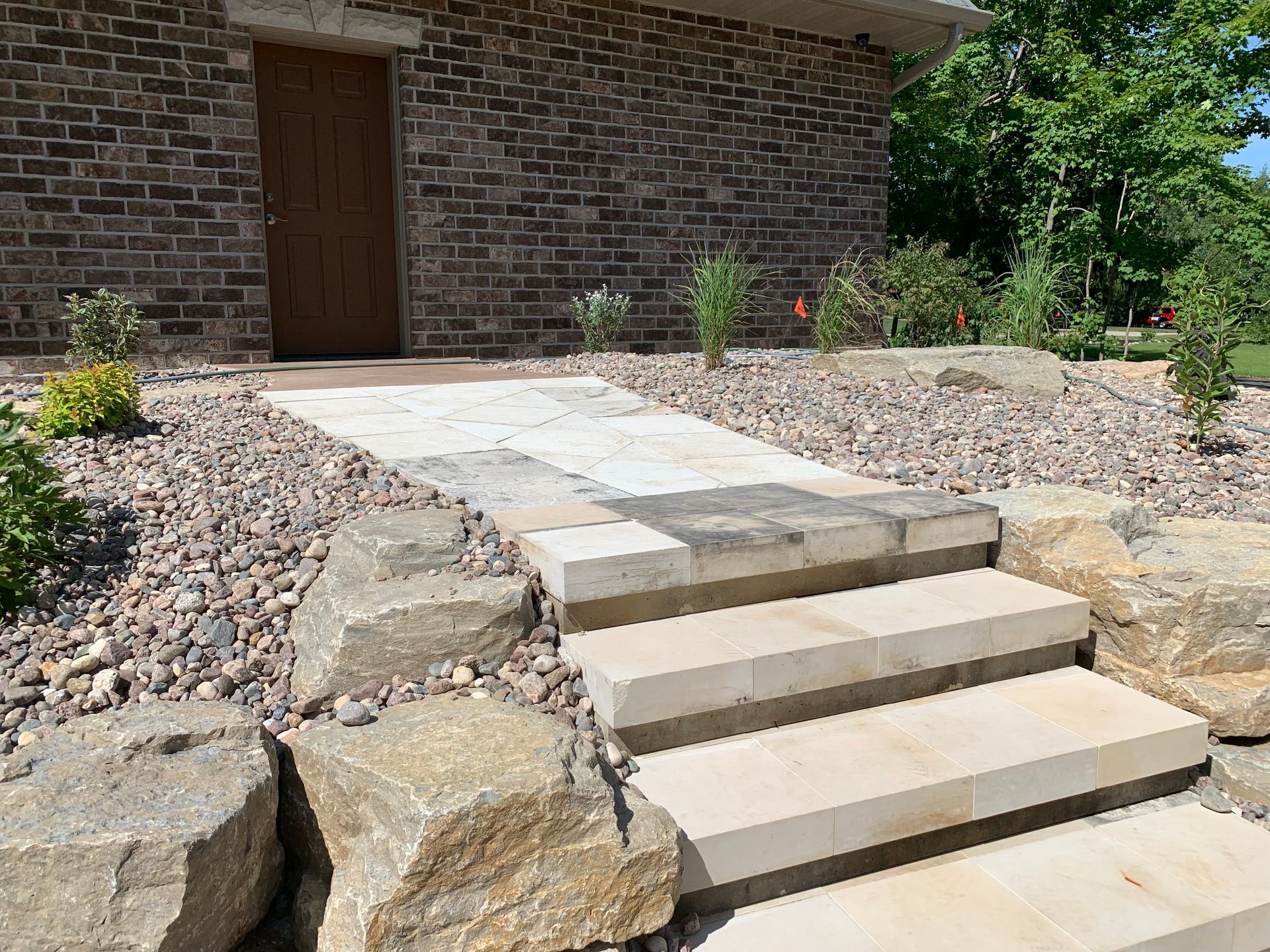 Stone steps leading to a brick building entrance with a concrete walkway and landscaping rocks
