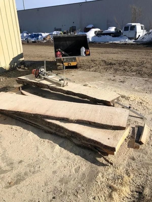 Construction site with a concrete pump truck and stacked wooden planks on muddy ground.