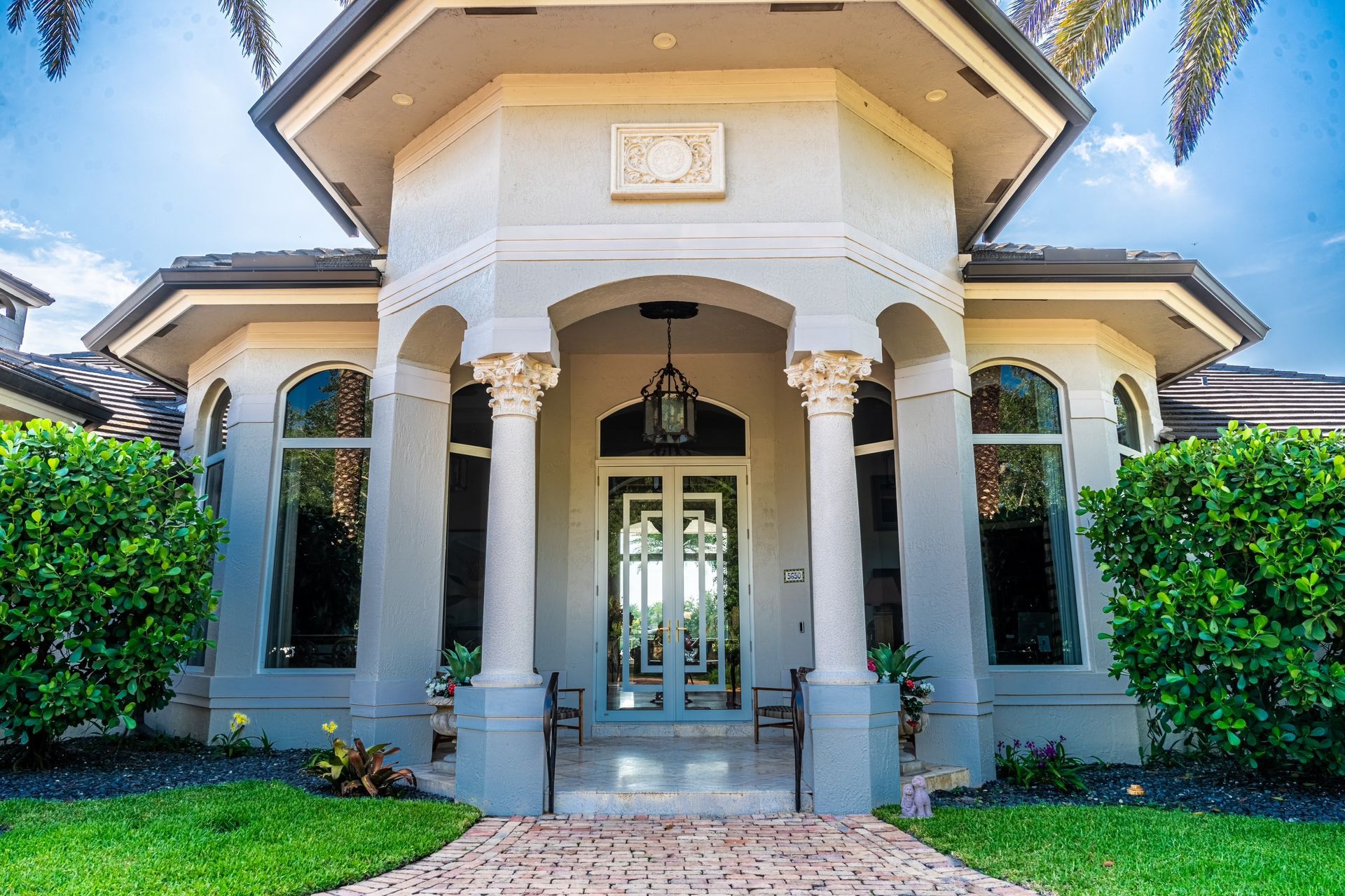 A large white house with a brick walkway leading to the front door.