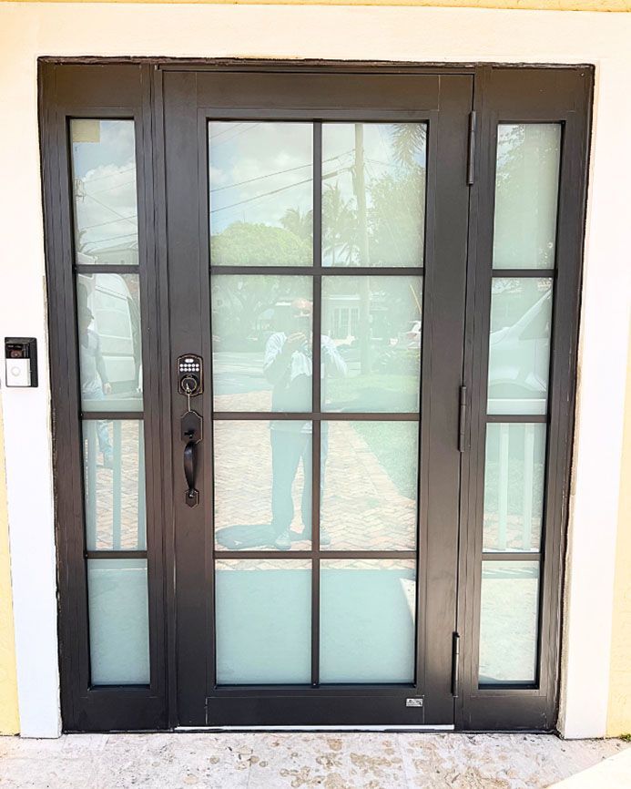 A black door with a white trim and a reflection of a person in it.