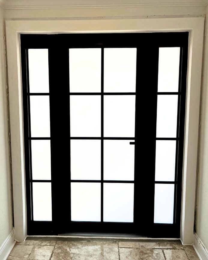 A black door with white windows in a hallway.