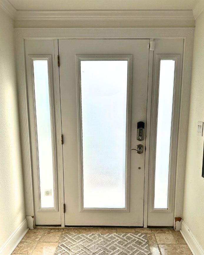 A white door with a rug in front of it in a hallway.