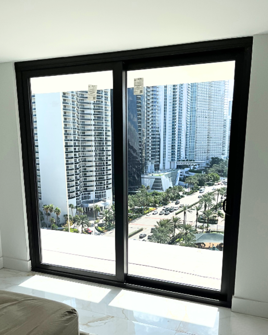 A bedroom with a sliding glass door and a view of a city.