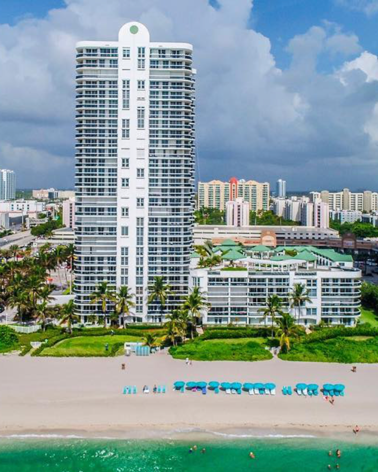 An aerial view of a beach with a tall building in the background