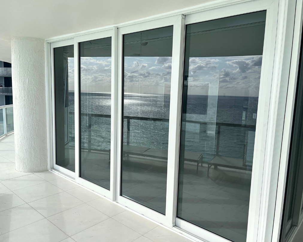 A balcony with sliding glass doors overlooking the ocean.