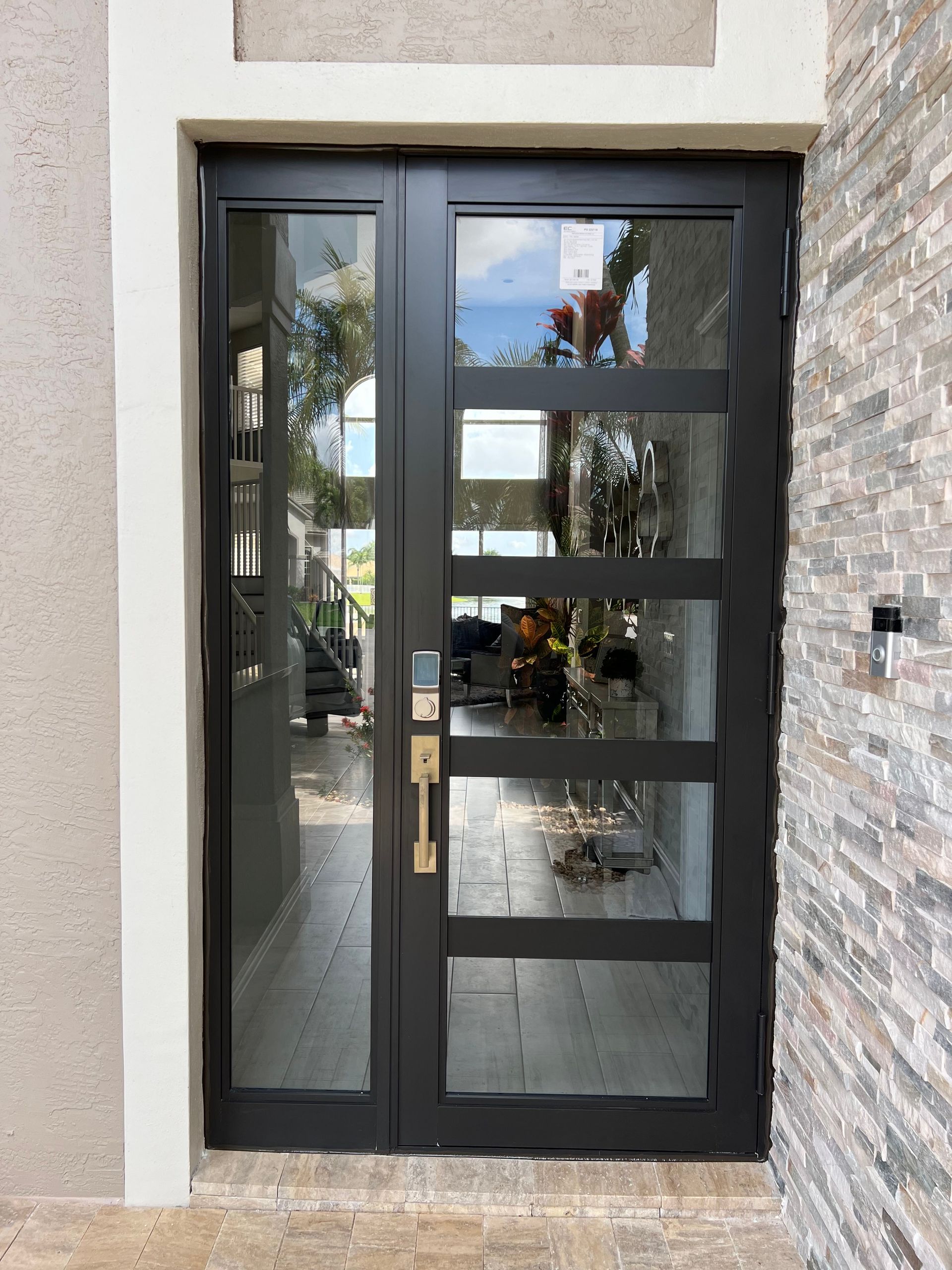A black door with a lot of glass is on a brick wall.