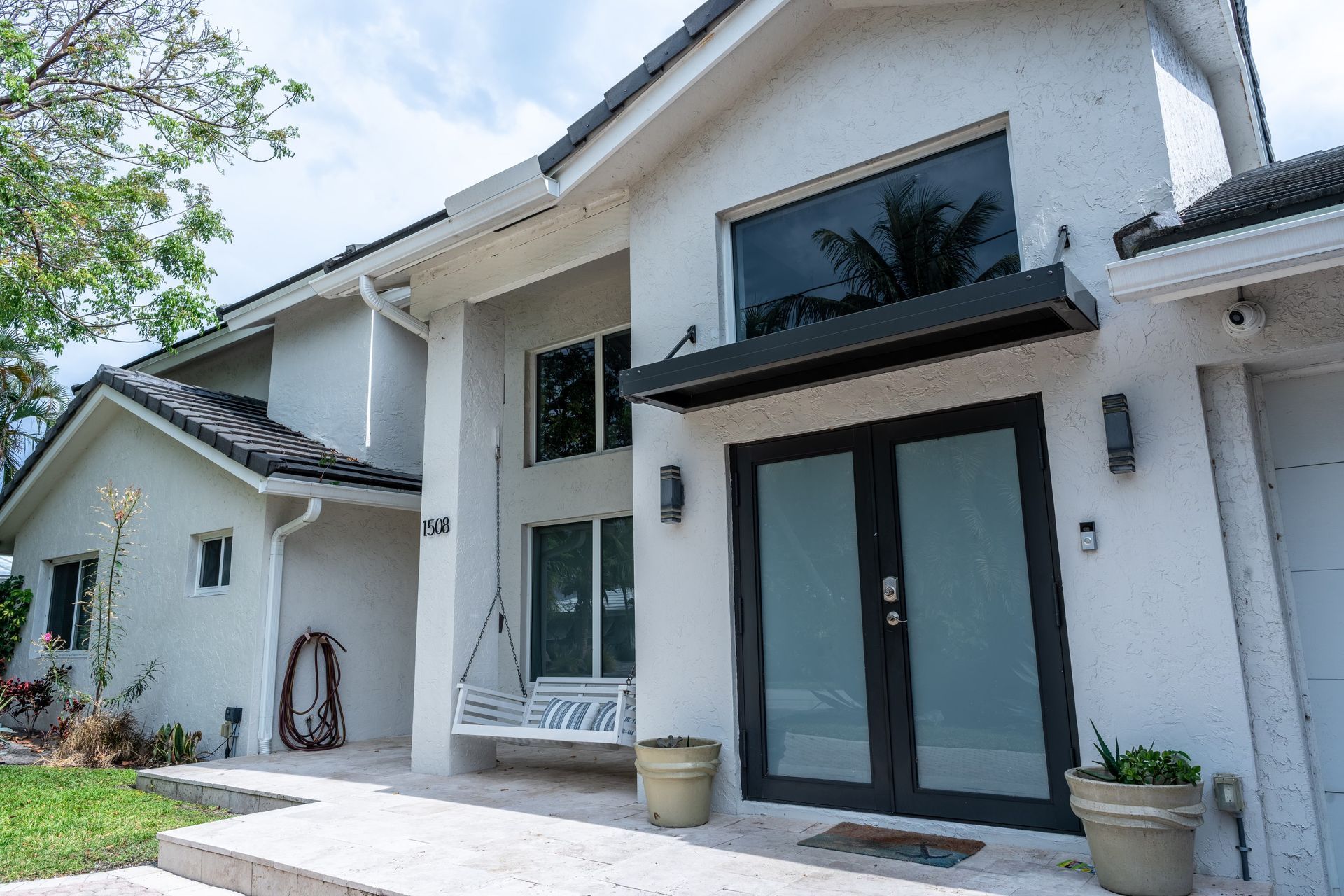 A white house with a black door and a bench in front of it.