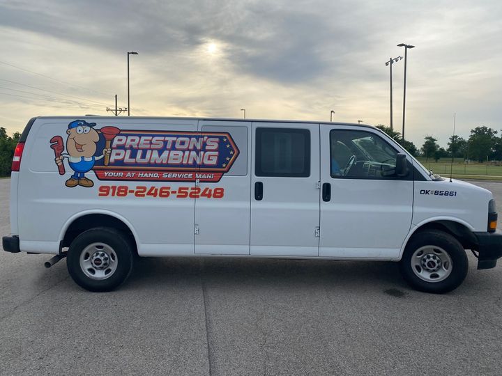 White Preston’s Plumbing van parked in a lot at sunset, with a large company logo on the side.