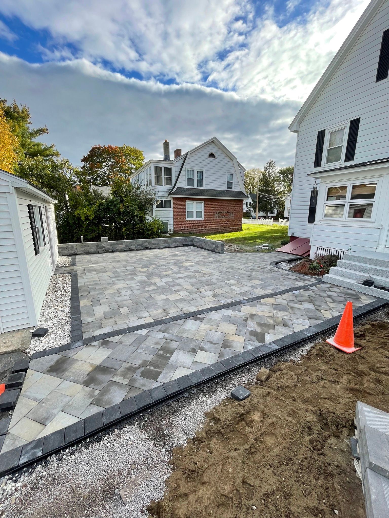 A brick driveway is being built in front of a white house.