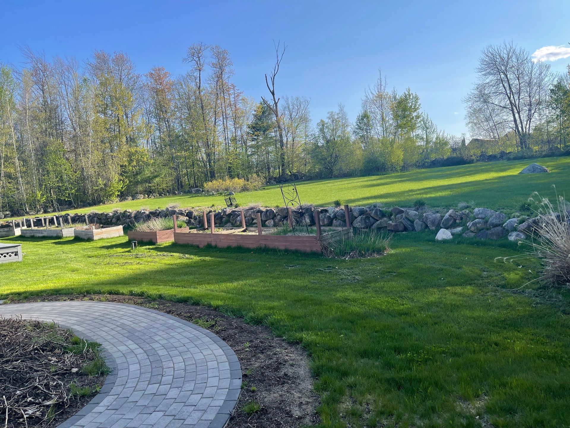 A brick walkway leading to a grassy field with trees in the background.