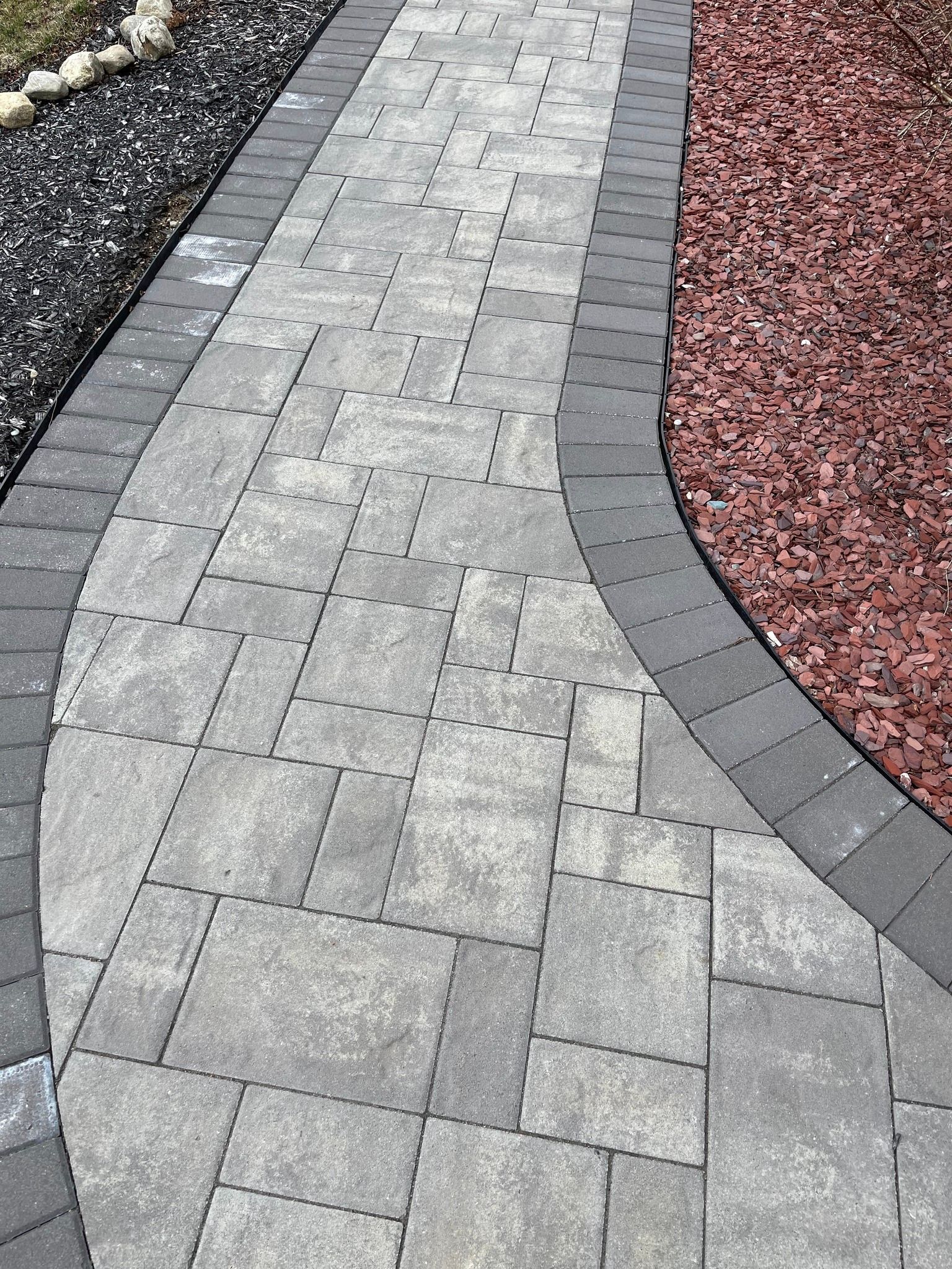 A walkway made of bricks and gravel in a garden.
