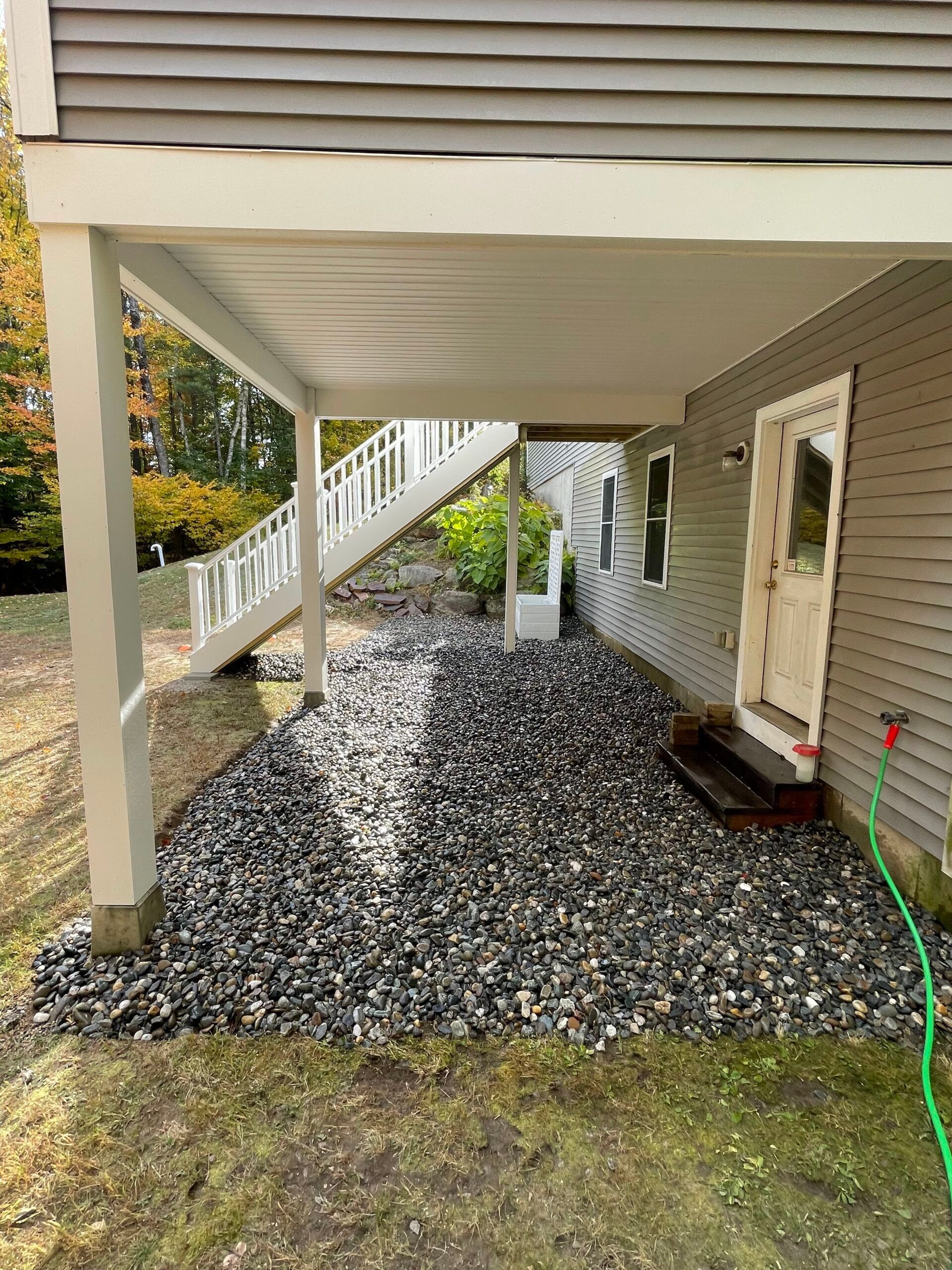 A house with a porch and stairs is sitting on top of a pile of gravel.