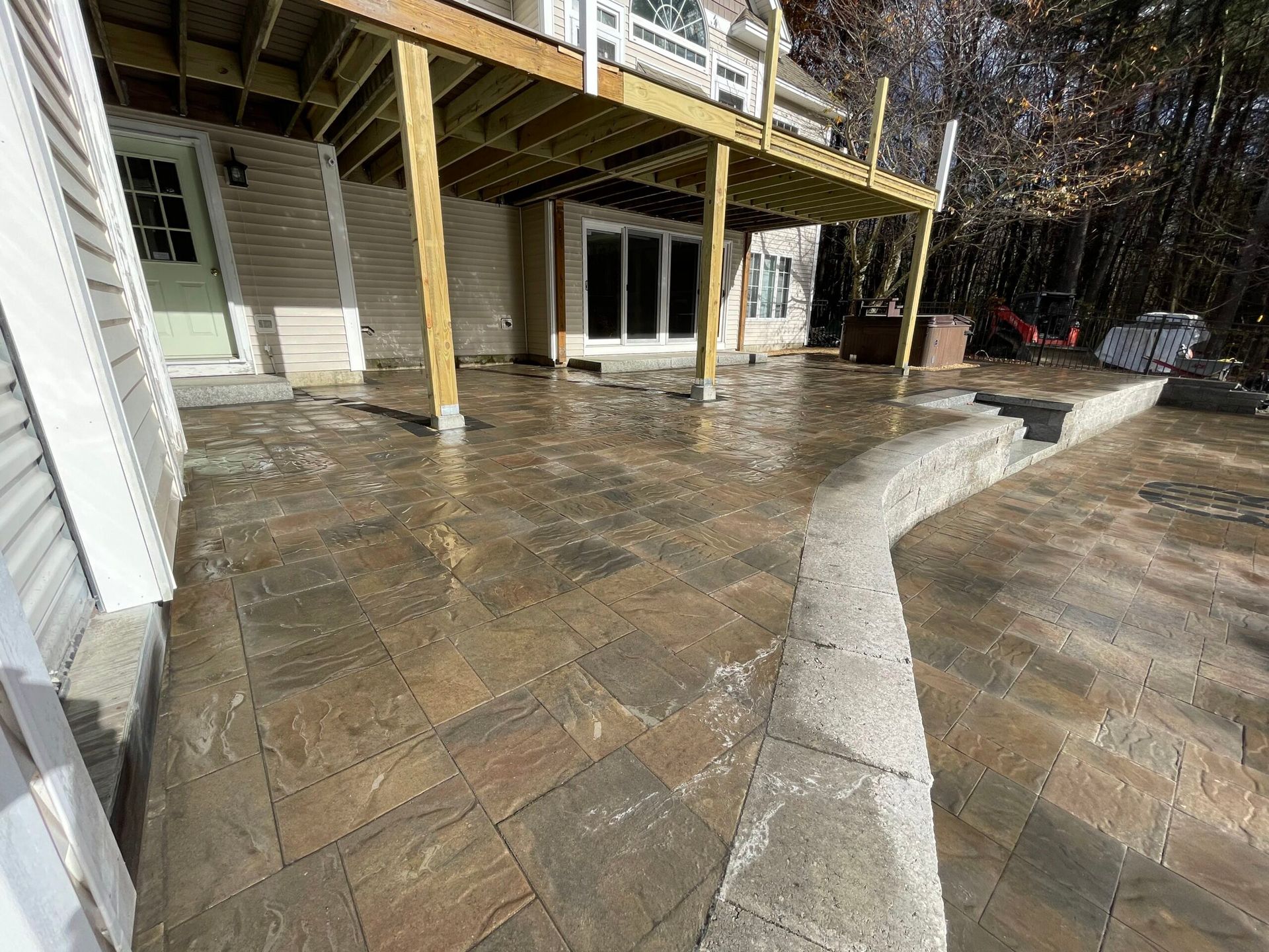 A large patio with a wooden deck and stairs in front of a house.