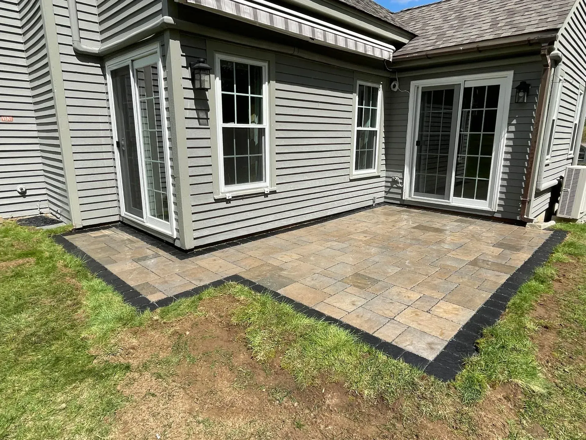 There is a patio in front of a house with sliding glass doors.