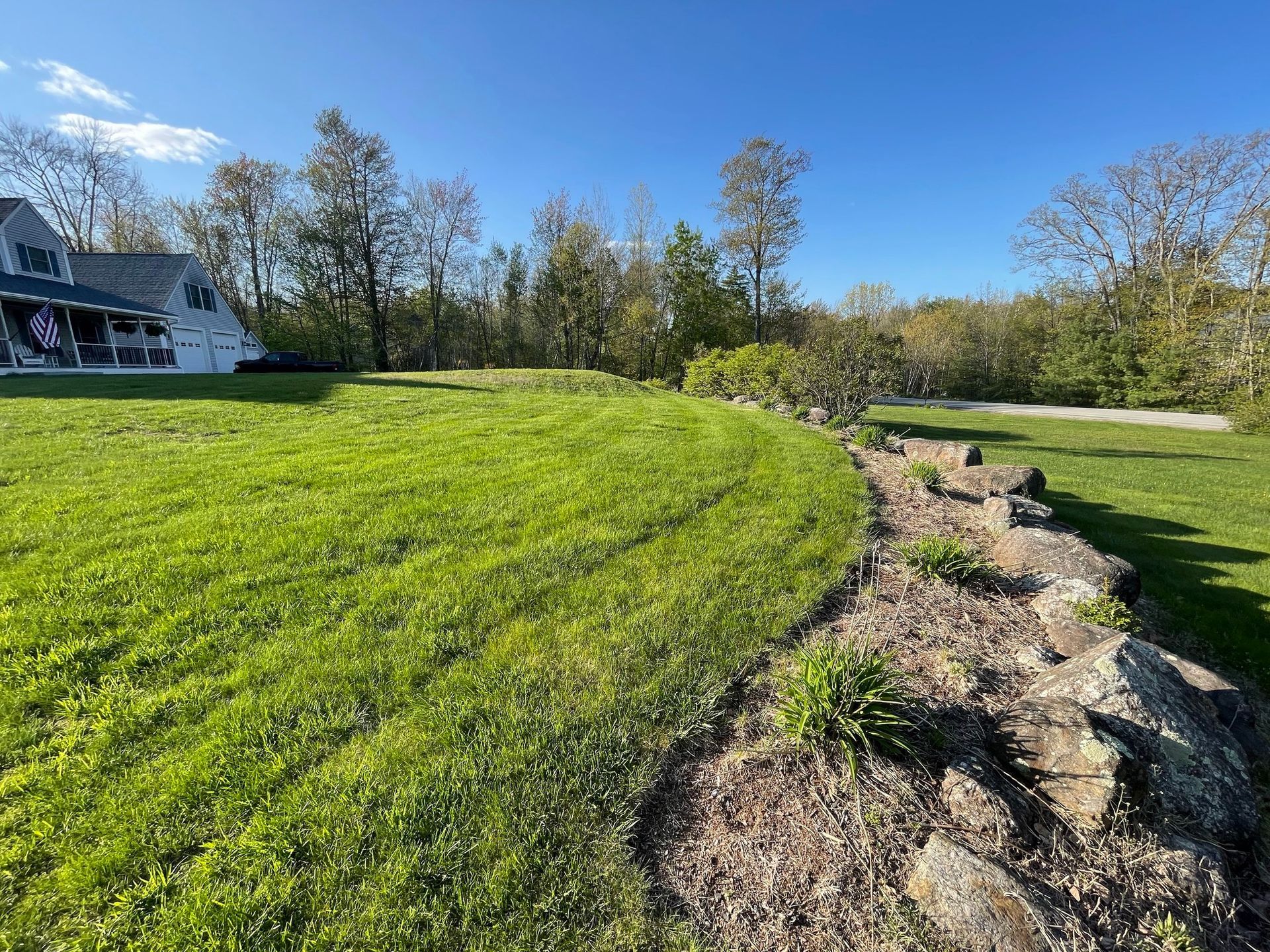 A large lush green field with a house in the background.