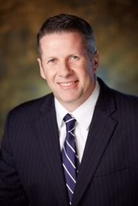 A man in a suit and tie is smiling for the camera.