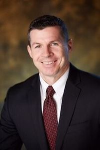 A man in a suit and tie is smiling for the camera.