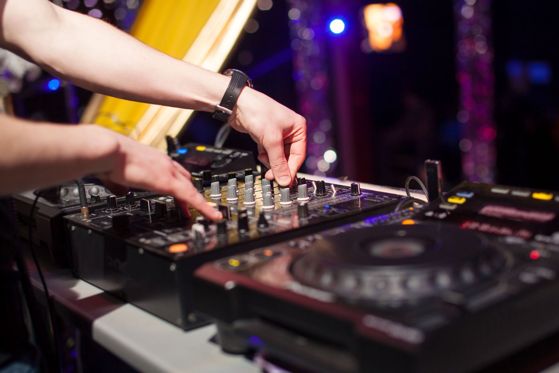 DJ adjusting audio mixing equipment at a club.