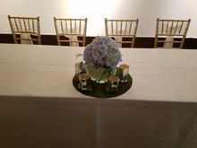Table setting with blue flowers, candles, and four chairs.
