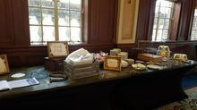 Table display in a room with windows; wooden boxes, ceramic items, and a book on the table.