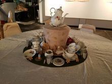 A table setting with tea cups, a teapot, and decorative items on a round platter.
