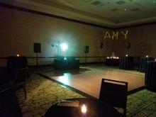 Empty event room with dance floor, DJ setup, tables, and 