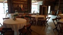 Reception hall with round tables covered in white linens and wooden chairs.