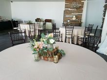 Round table set for event with centerpiece; other tables and chairs in room.