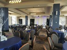 Event space with round tables, navy tablecloths, and chairs, ready for guests.