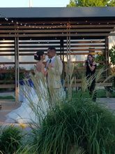 Wedding ceremony with couple in front of wooden structure; a photographer captures the moment.