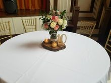 Round table set for event with flower arrangement, candles, and '10' on a wooden base.