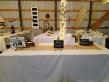Wedding reception table with white tablecloth, burlap runner, and decorations.
