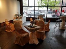 Event space with draped tables and chairs, by a large window overlooking a street.