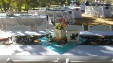 Outdoor wedding reception table setting with floral centerpieces and decorated tables.